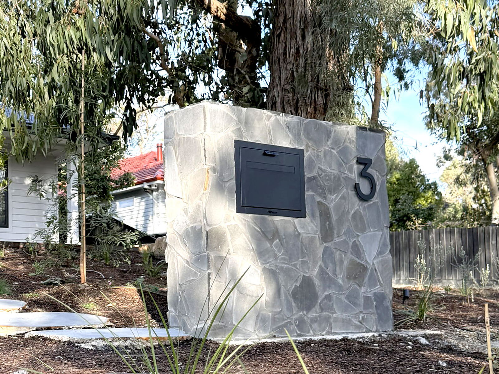 Close-up of the hand-cut bluestone crazy paving on the postbox, with the recessed letterbox and house number